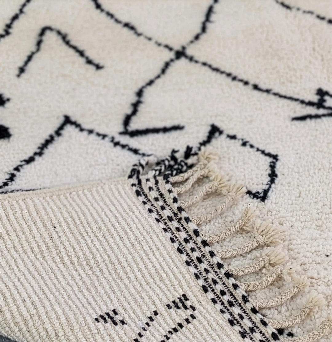 Close-up of a textured rug with geometric pattern and tassels.