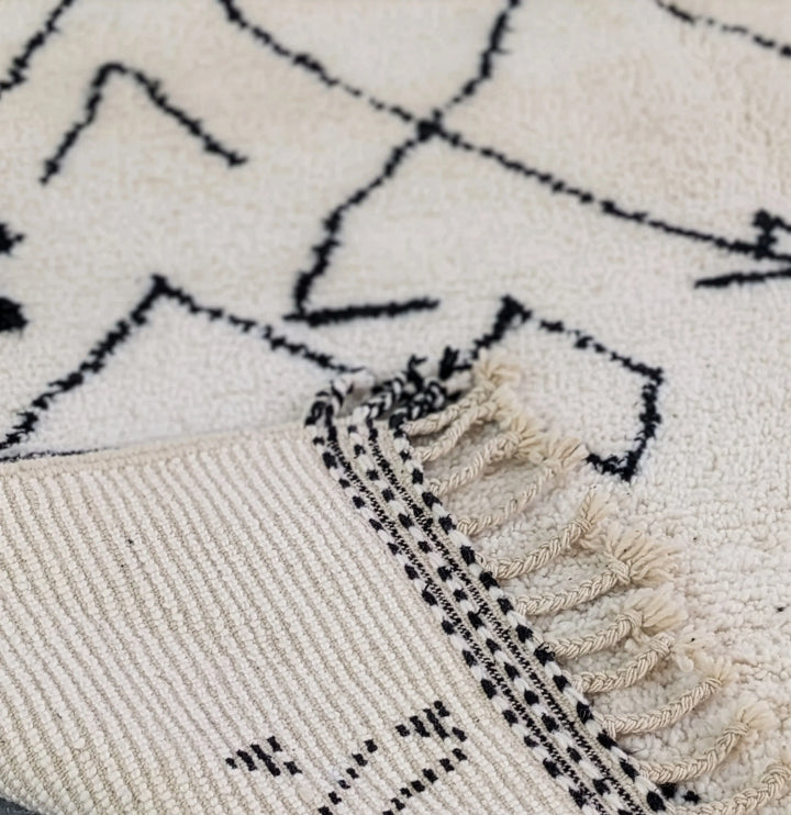 Close-up of a textured rug with geometric pattern and tassels.