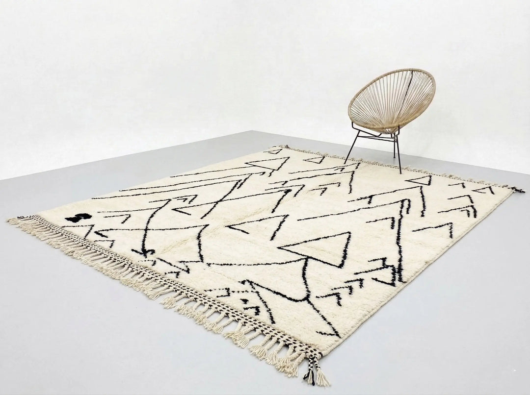 Beige rug with black abstract patterns on a light gray floor.