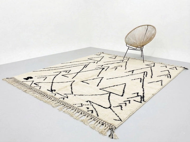 Beige rug with black abstract patterns on a light gray floor.