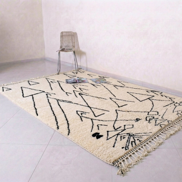Beige rug with black geometric pattern on a light gray floor.