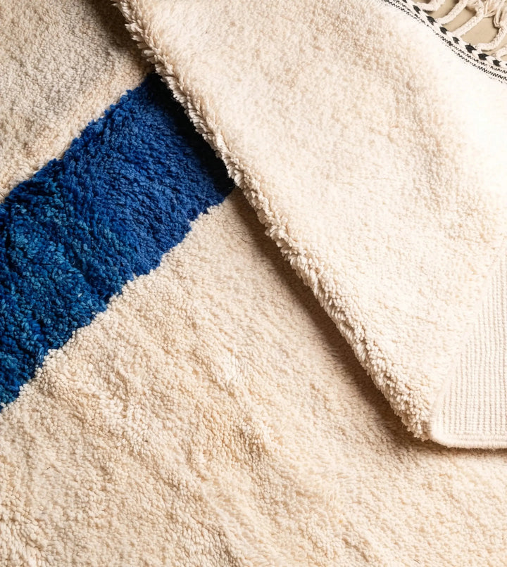 Close-up of a textured fabric with a blue stripe and beige background