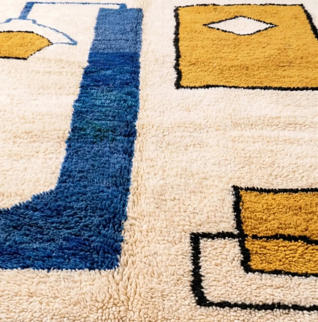 Close-up of a textured rug with geometric patterns in blue, yellow, and beige.