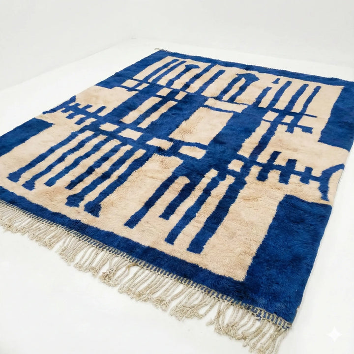 Modern boho style area rug in electric blue and ivory. Custom Beni Mrirt wool carpet hanging on display, perfect for contemporary living rooms.