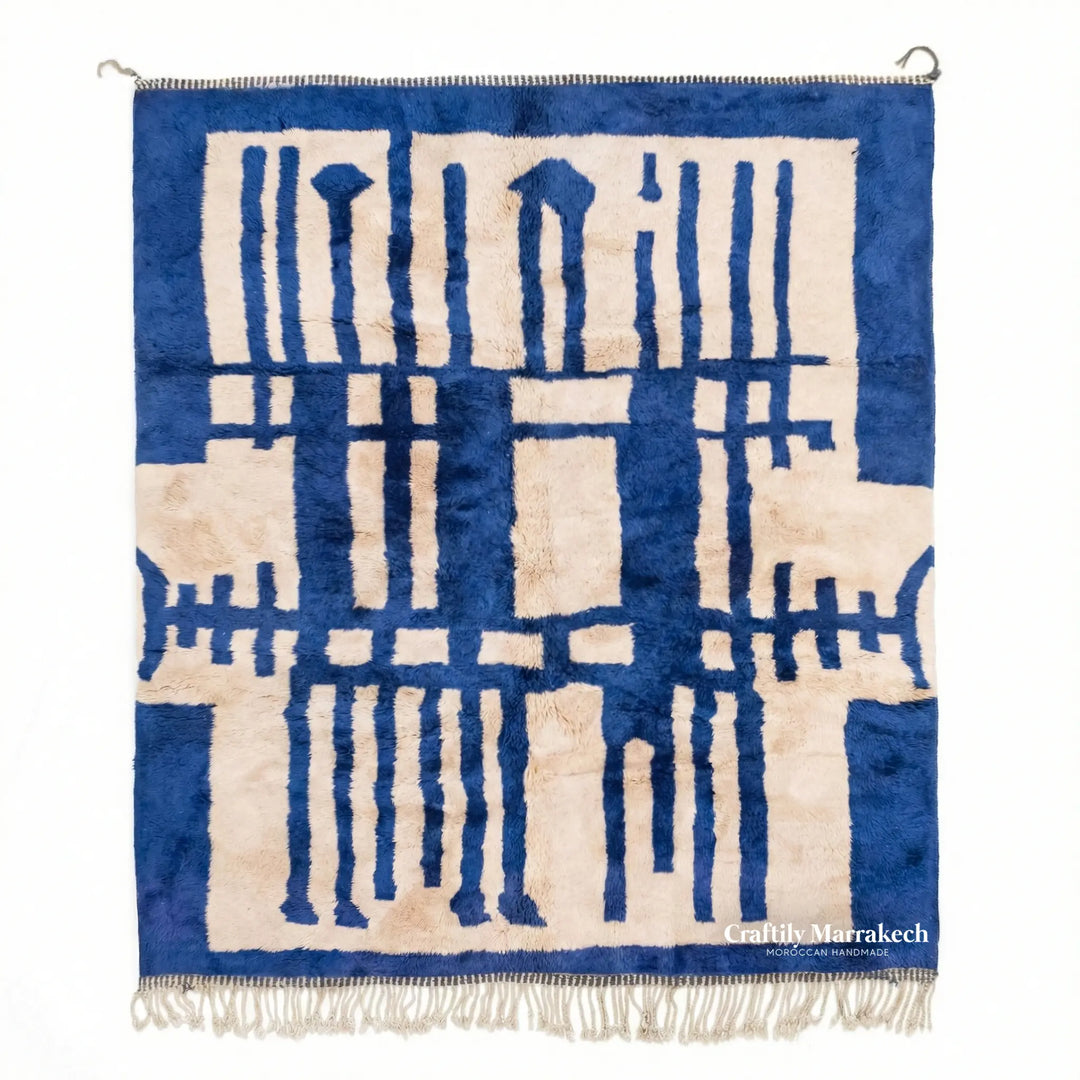 Blue and cream Beni Mrirt rug with abstract design hanging on rod.