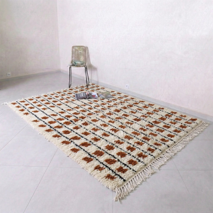 Beige and brown patterned rug on a light gray floor with a chair in the corner.